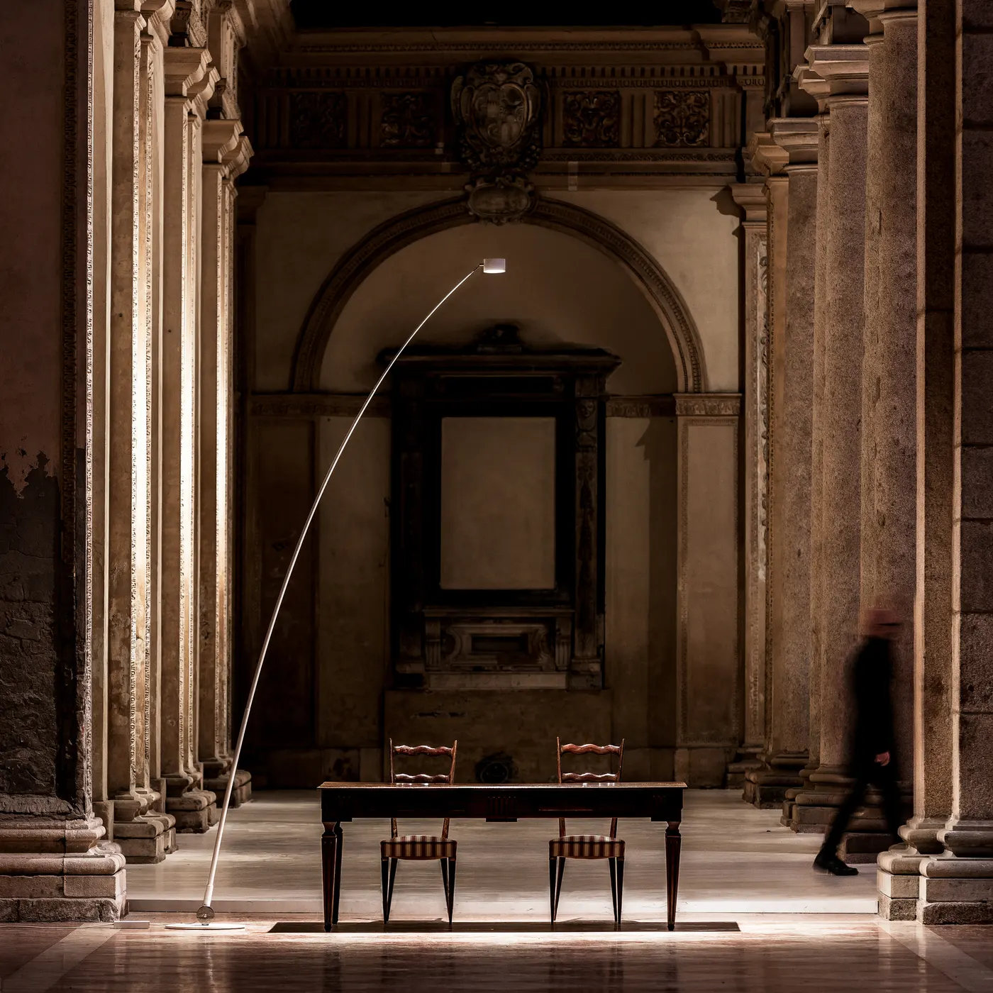 Spazio rinascimentale con tacolo in legno d'epoca al centro, con grande luce contemporanea a illuminare il tavolo